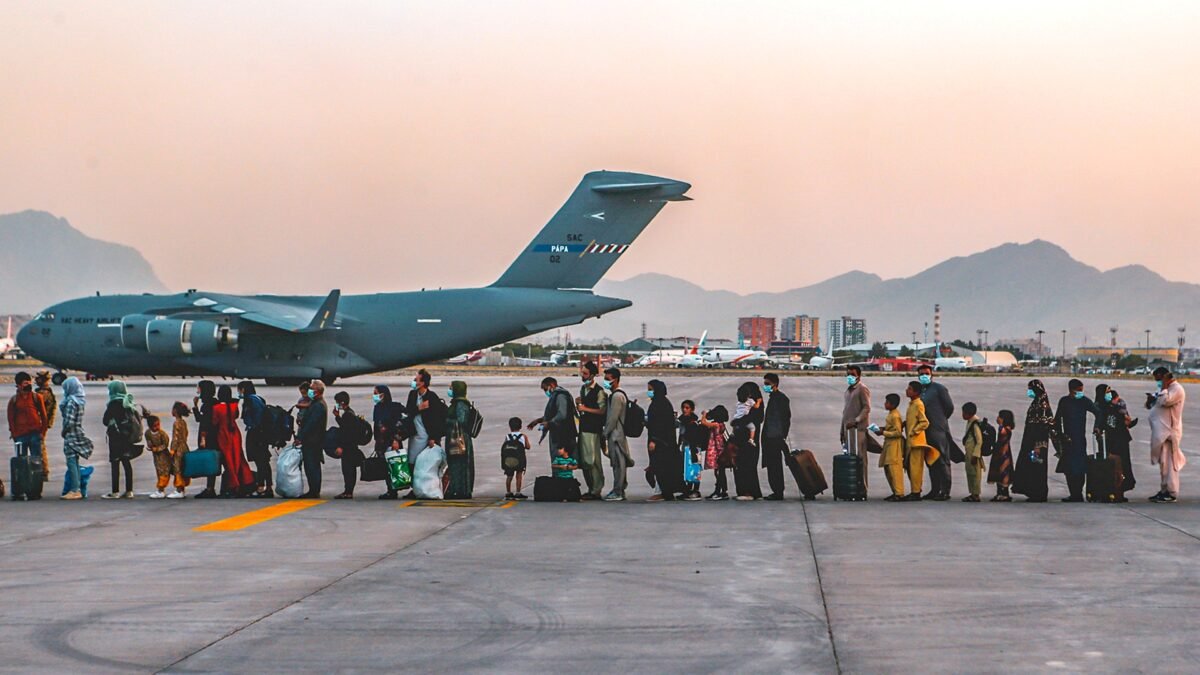 File photo (23 August 2021): Afghan evacuees, including women and children carrying luggage, wait to board a C-17 transport aircraft at Hamid Karzai International Airport in Kabul during the 2021 evacuation. Photo: Sgt. Isaiah Campbell, US Marine Corps (public domain), via Wikimedia Commons.