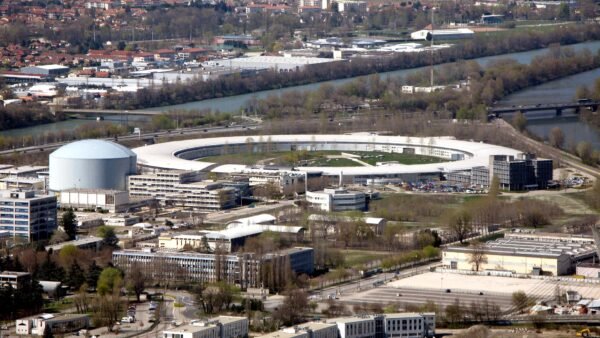Aerial view of the European Synchrotron Radiation Facility in Grenoble, France, showing its ring-shaped synchrotron building.