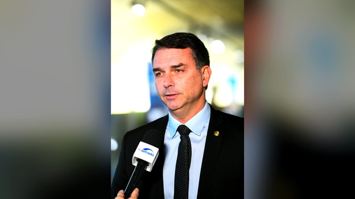 Senator Flávio Bolsonaro speaking into a TV Senado microphone during an interview in Brasília.