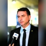 Senator Flávio Bolsonaro speaking into a TV Senado microphone during an interview in Brasília.