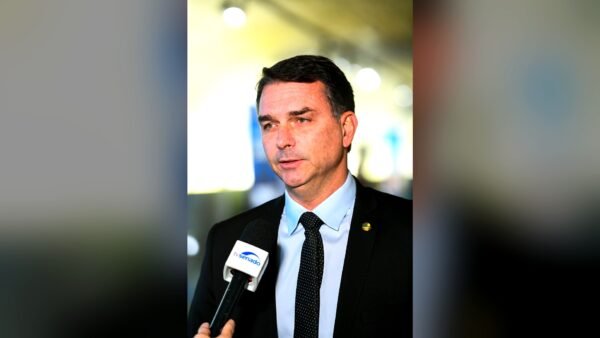 Senator Flávio Bolsonaro speaking into a TV Senado microphone during an interview in Brasília.