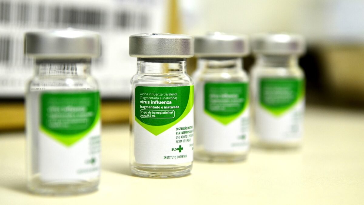 Vials of H1N1 influenza vaccine with green and white labels arranged on a table.