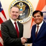 US Trade Representative Jamieson Greer shaking hands with Indian Commerce and Industry Minister Piyush Goyal in front of the US and Indian flags.