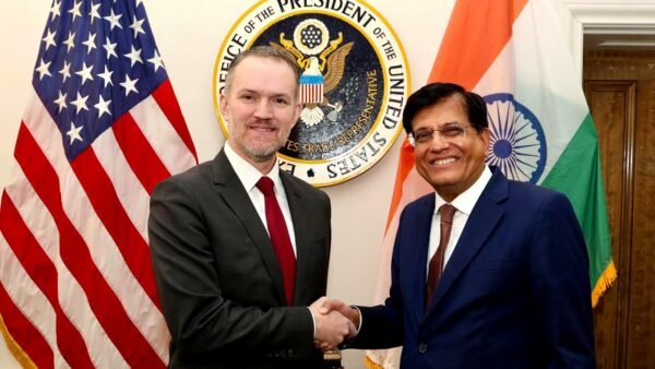 US Trade Representative Jamieson Greer shaking hands with Indian Commerce and Industry Minister Piyush Goyal in front of the US and Indian flags.