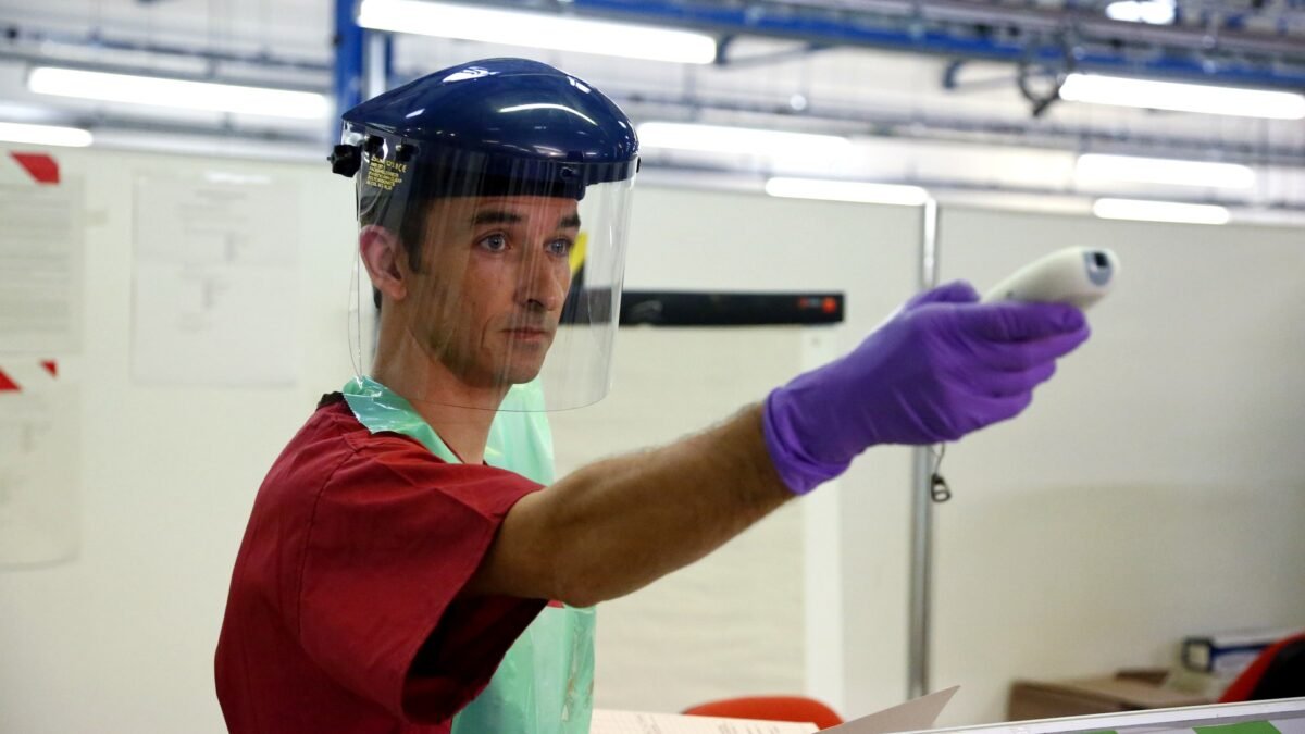 File photo: a health worker in protective gear demonstrates temperature screening with an infrared thermometer during an Ebola-response training exercise.