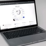 A silver MacBook Pro laptop open on a plain background, showing its keyboard and screen.