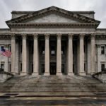Grand neoclassical federal courthouse facade in Manhattan with an American flag flying, overcast daytime sky