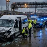 Damaged white minibus on a railway loading platform at dusk as emergency services respond to the Channel Tunnel collision at Coquelles, France.