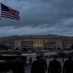The Pentagon at dusk with the American flag flying, where retired generals and admirals are urging the abandonment of plans to livestream Nidal Hasan's firing-squad execution