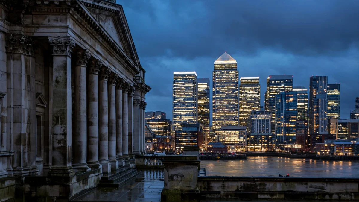 Canary Wharf financial towers glowing at dusk beside a historic London facade.