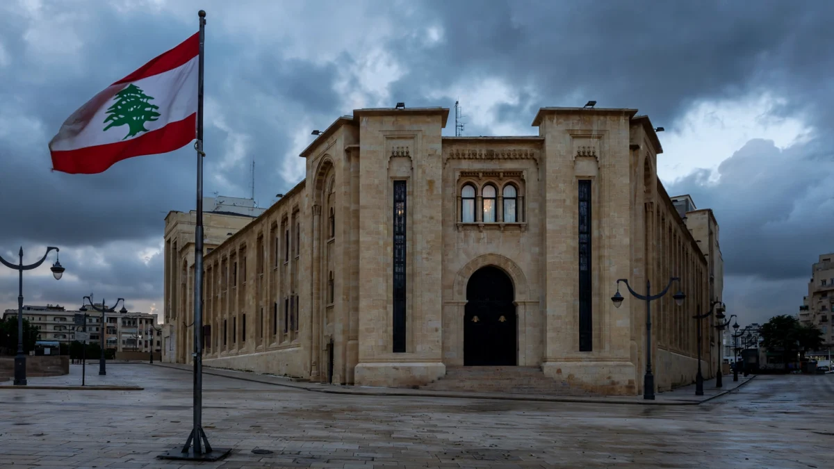 Lebanese parliament building in Beirut under a dramatic overcast sky with the Lebanese flag flying.