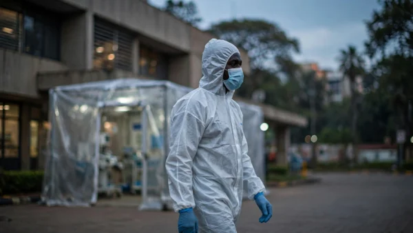 A health worker in protective equipment outside a hospital isolation unit in Nairobi, Kenya, at dusk.