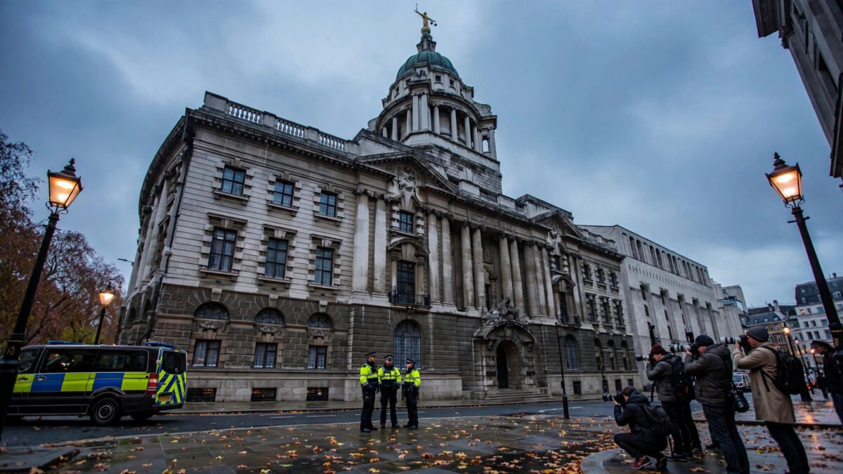 The Old Bailey in London at dusk, with police officers, a police van and press photographers gathered outside the historic court building.