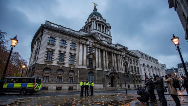 The Old Bailey in London at dusk, with police officers, a police van and press photographers gathered outside the historic court building.