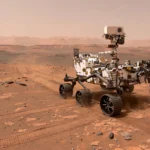 Photorealistic illustration of NASA's six-wheeled Perseverance rover driving across Mars' Jezero Crater rim, red dust, distant crater edge, deep blue sky.