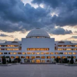 Pakistan's Parliament House in Islamabad at dusk, its white domed building lit against a cloudy evening sky