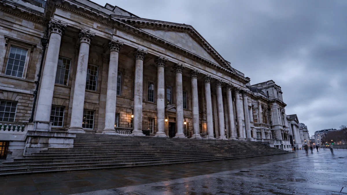 Historic stone Crown Court building with tall columns in London under an overcast evening sky