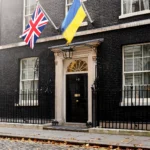 10 Downing Street in London with the British Union Jack and Ukrainian flags flying side by side above the black front door on an autumn morning