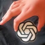 File photo: the OpenAI logo on a sticker held in a hand.