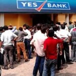 Depositors queue outside a Yes Bank branch, with the bank's blue-and-red YES BANK sign visible above the entrance.